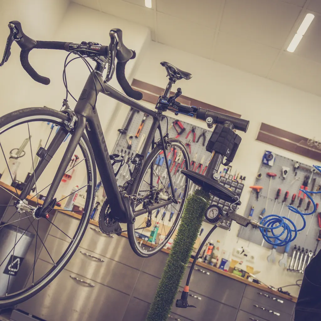 A road bicycle mounted on a workshop stand with cycle tools arranged behind it.