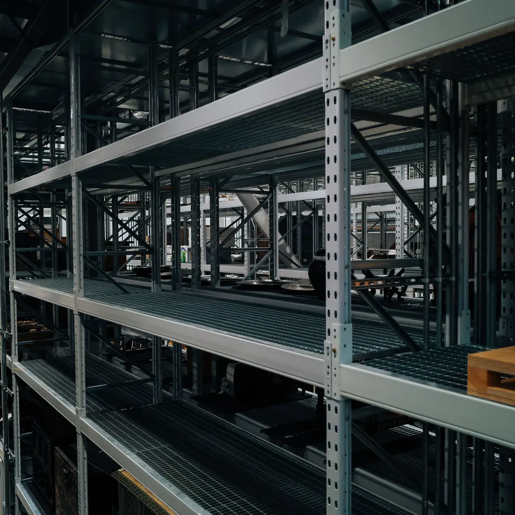 Rows of empty galvanized-steel storage shelving with perforated uprights and cross braces.