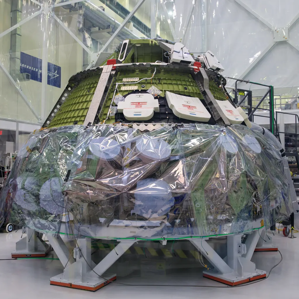 A spacecraft crew module under assembly in a clean room.