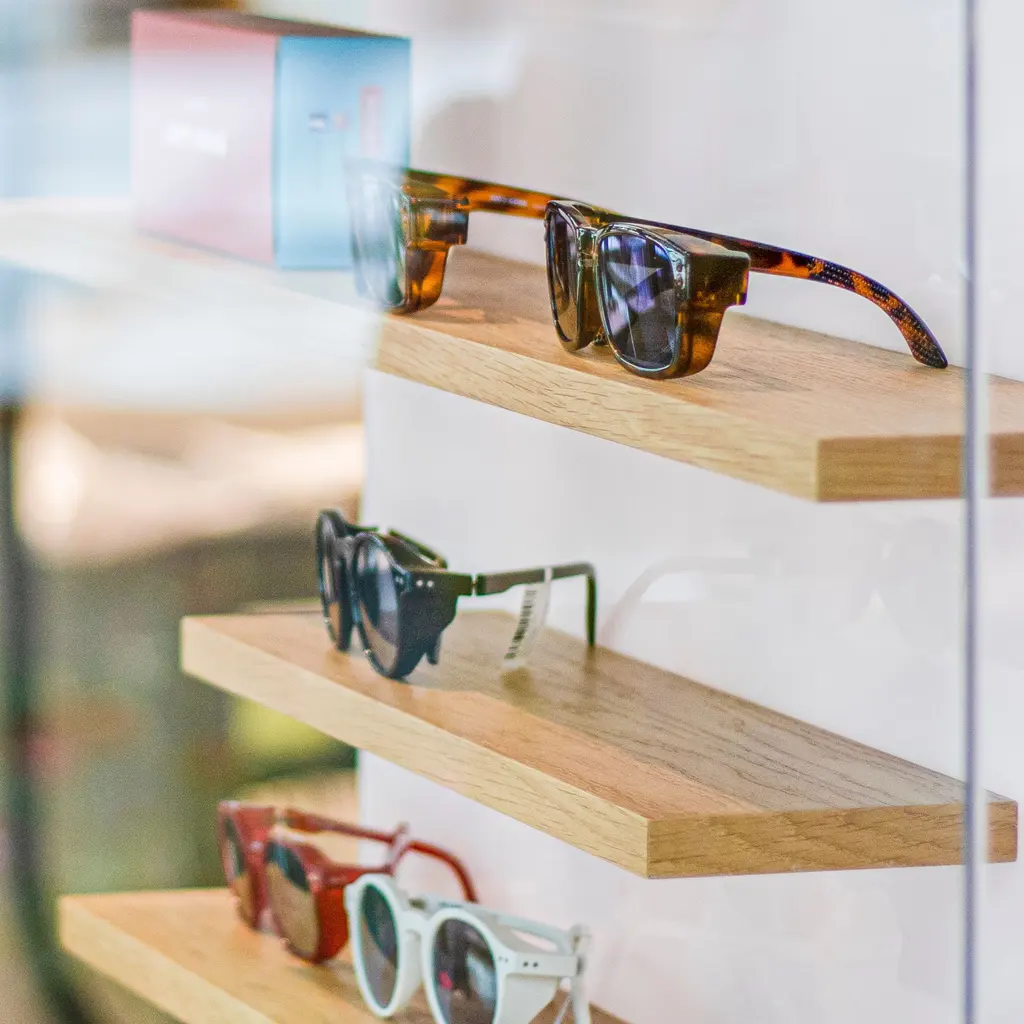 Sunglasses are arranged on wooden shelves in a fashion-accessories display.