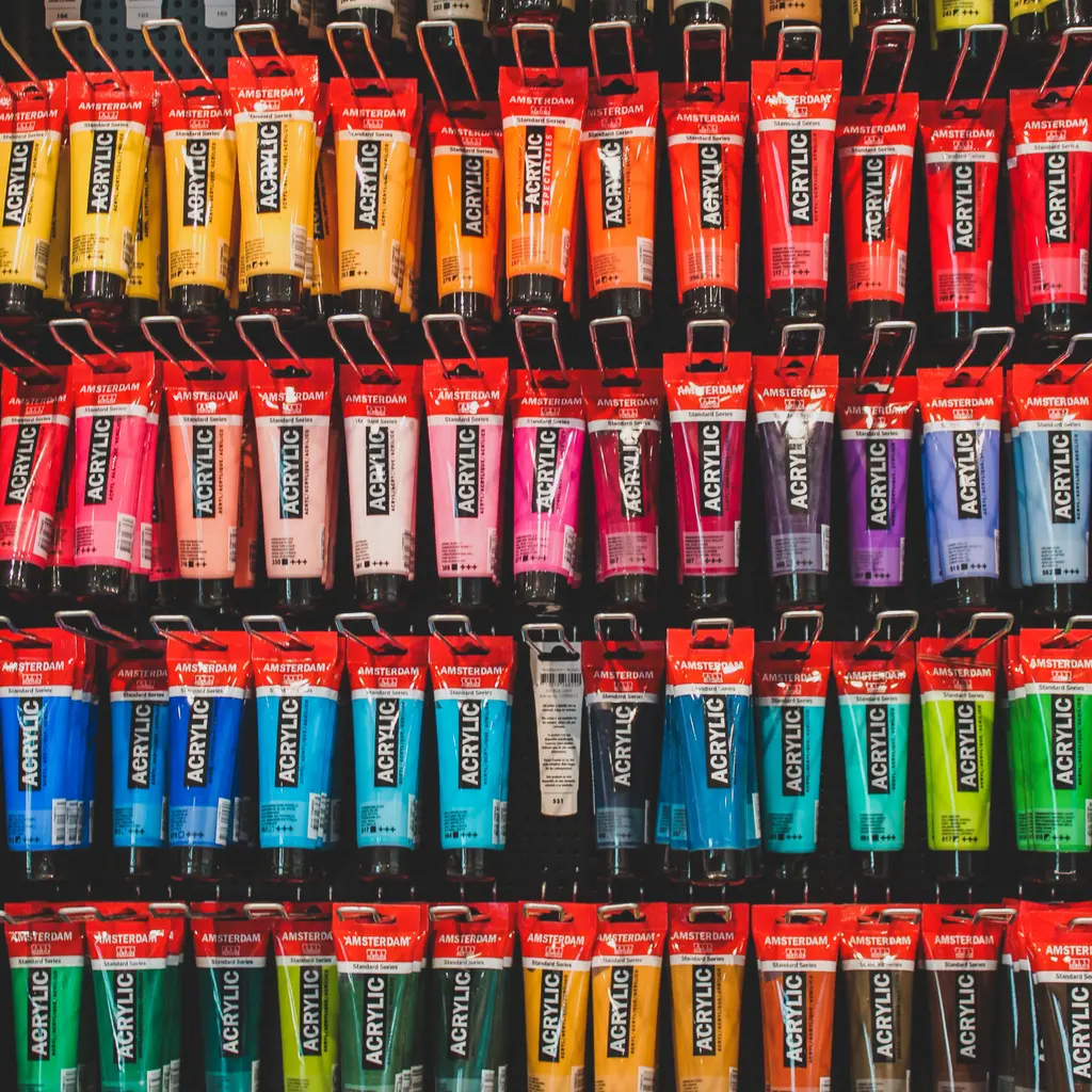 Acrylic paint tubes hang in color-organized rows on an art-supply display rack.