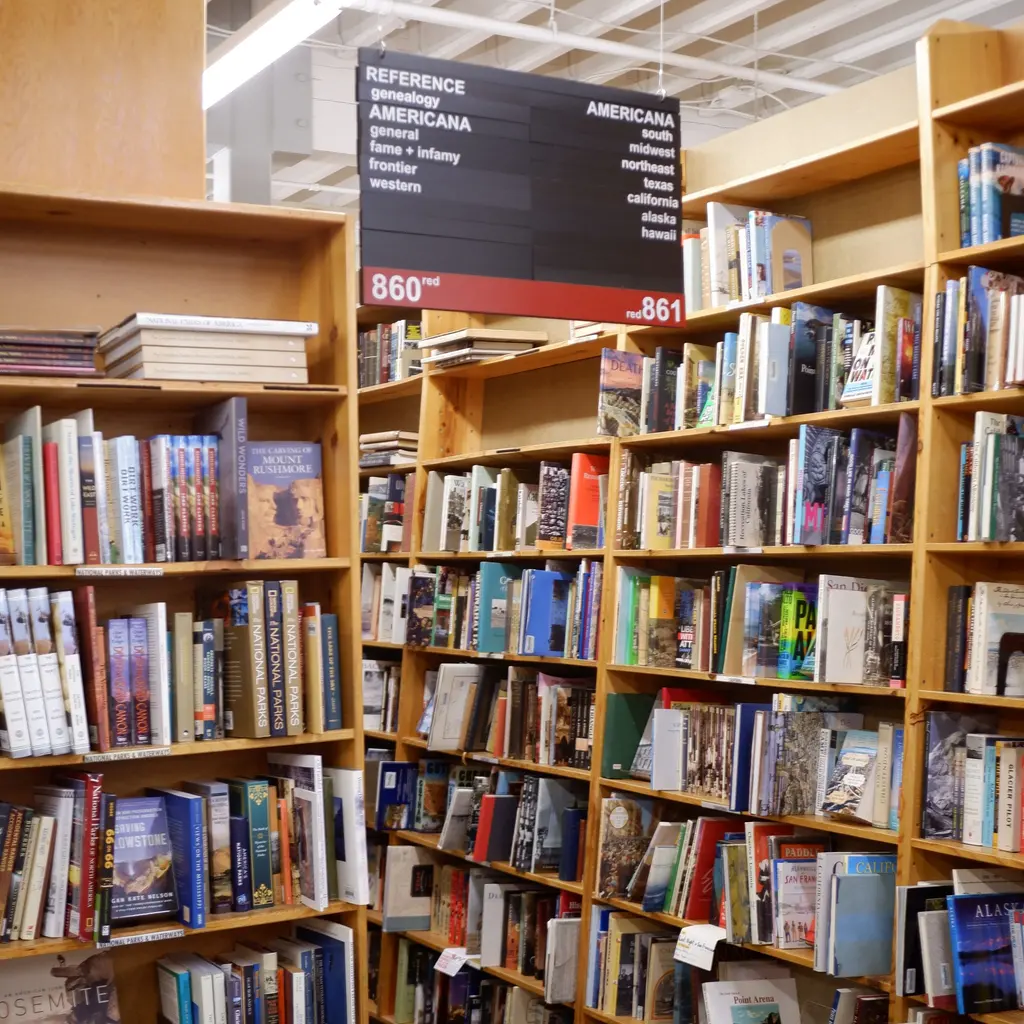 Books fill display shelves beneath an Americana section sign in a bookstore aisle.