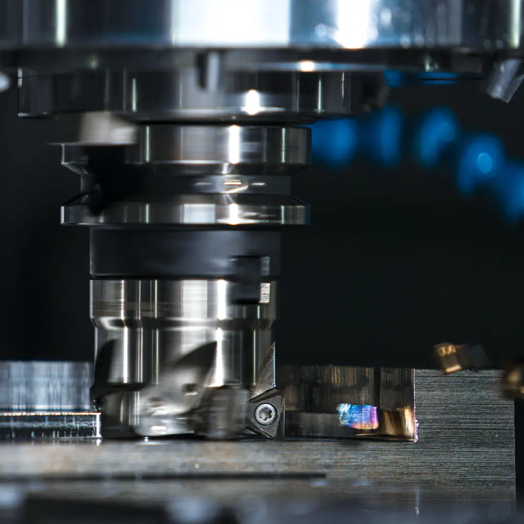A rotating face mill cuts a metal workpiece, leaving a freshly machined surface.