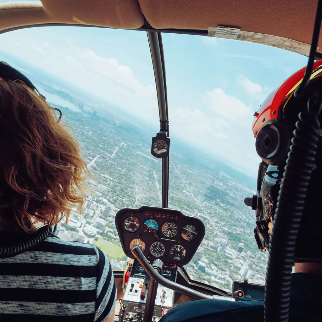 View past headset-wearing occupants and helicopter instruments toward the city below.