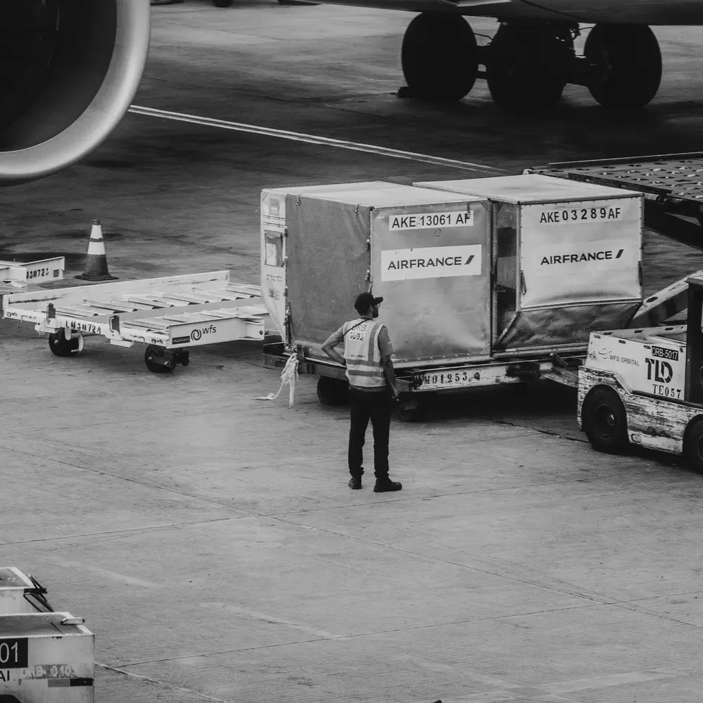Air-freight containers and a ground worker beside an aircraft.