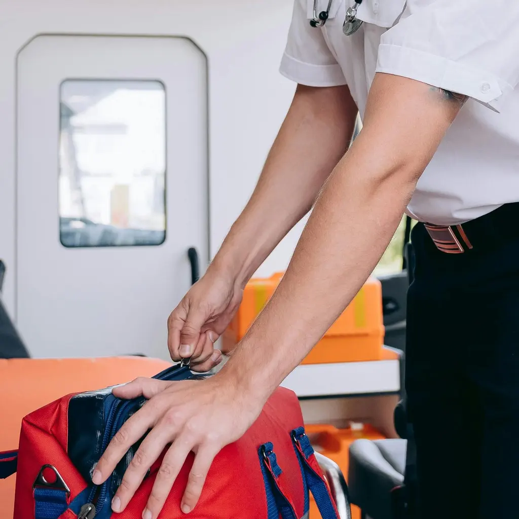 Hands handle a red medical bag inside an ambulance.