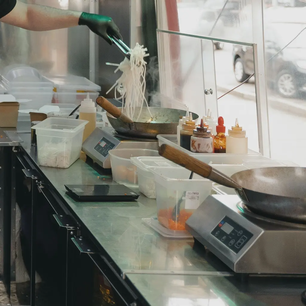 A cook preparing food at a wok in a food-truck kitchen.