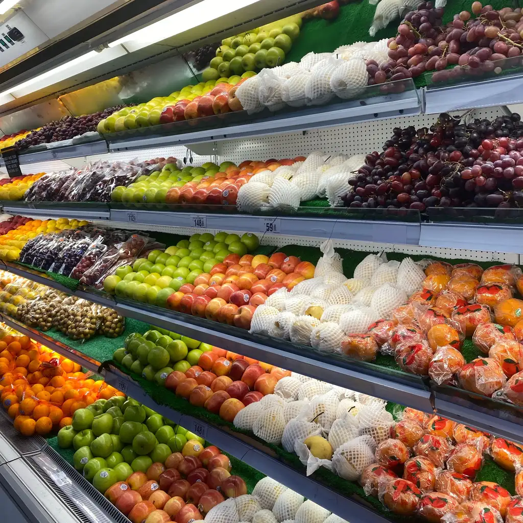 Fruit is arranged on tiered shelves in a grocery display.