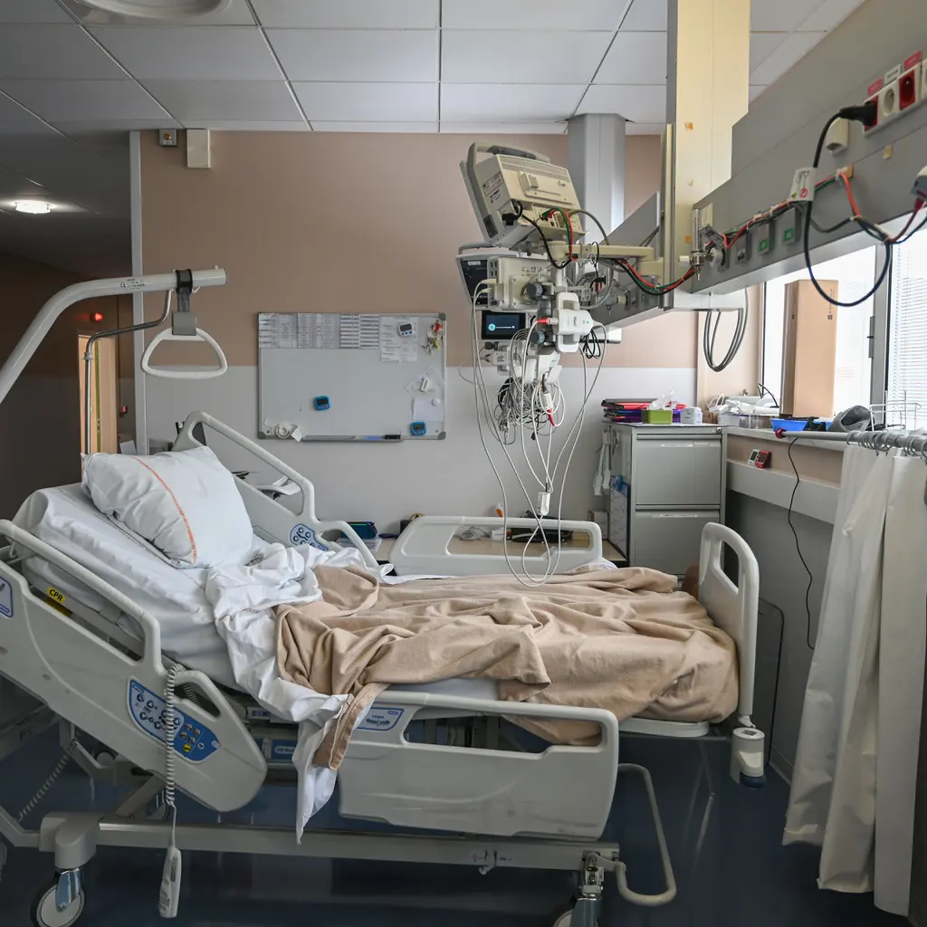 An empty hospital bed beside monitoring equipment.