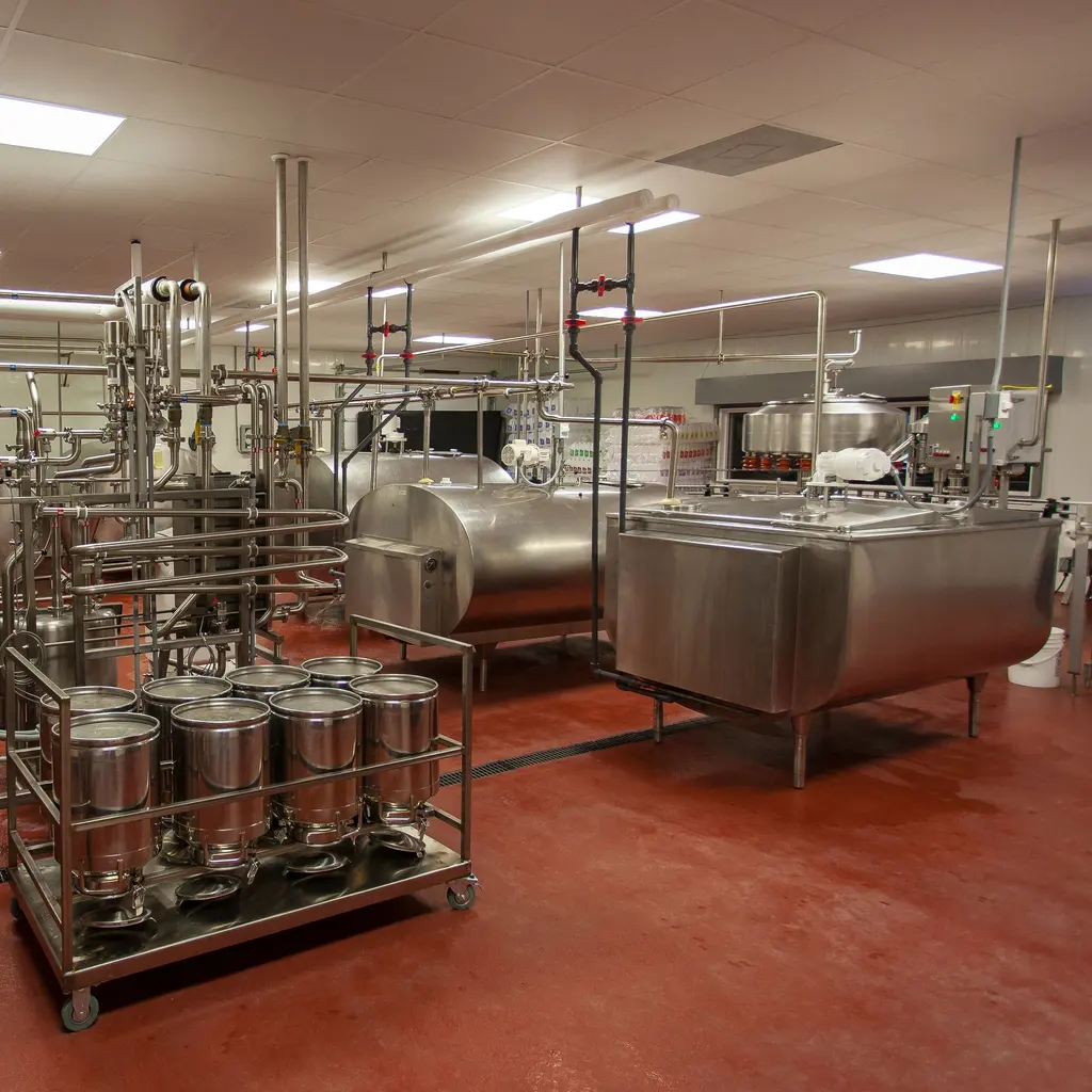 Stainless processing vessels and pipework in a milk-processing room.