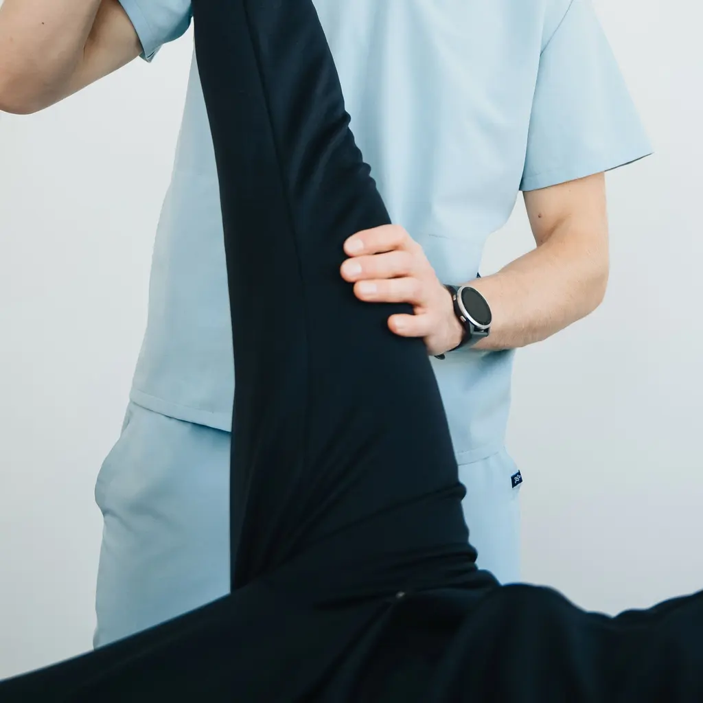 A therapist supports a patient's raised leg during a physical-therapy session.