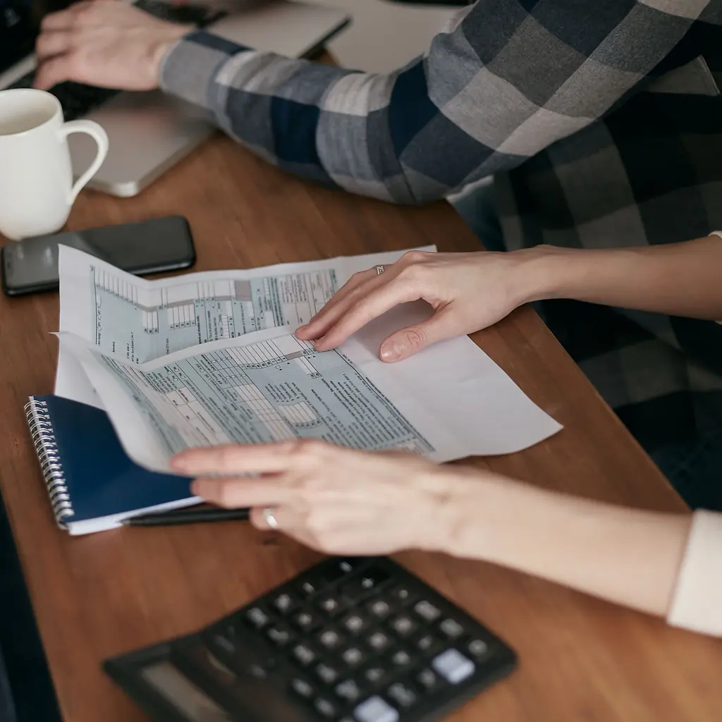 Hands review paper U.S. tax forms at a desk.