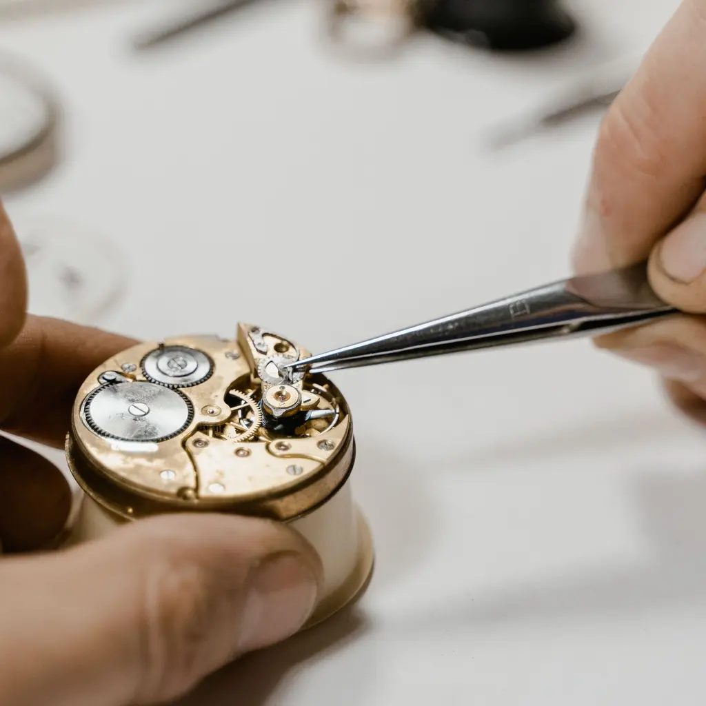 Hands adjusting an exposed watch movement with tweezers.