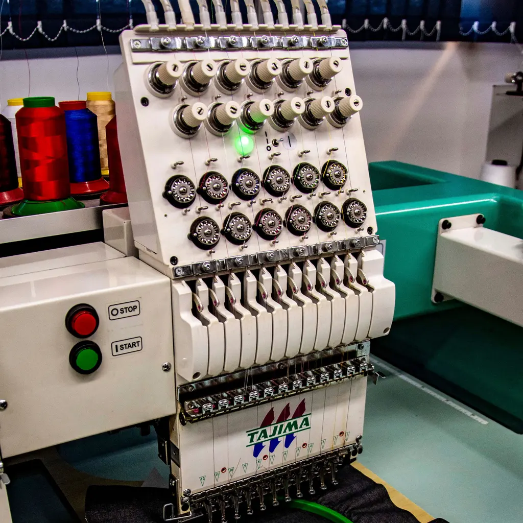 Thread spools sit beside an embroidery-machine head.