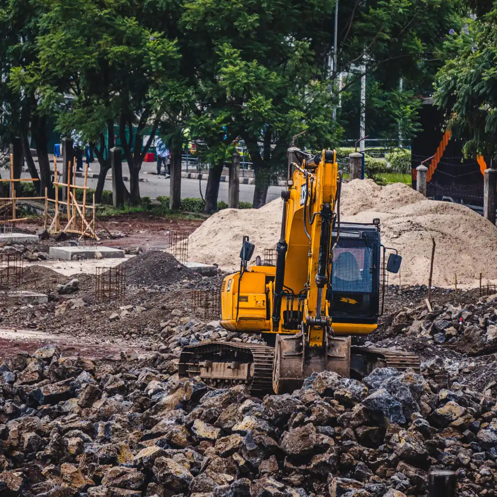 A yellow excavator amid rubble and earth at a construction site.