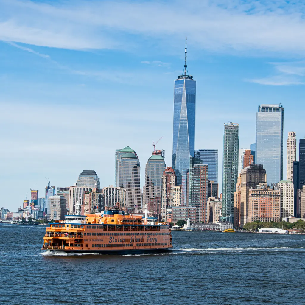 A passenger ferry crosses the harbor in front of the New York City skyline.