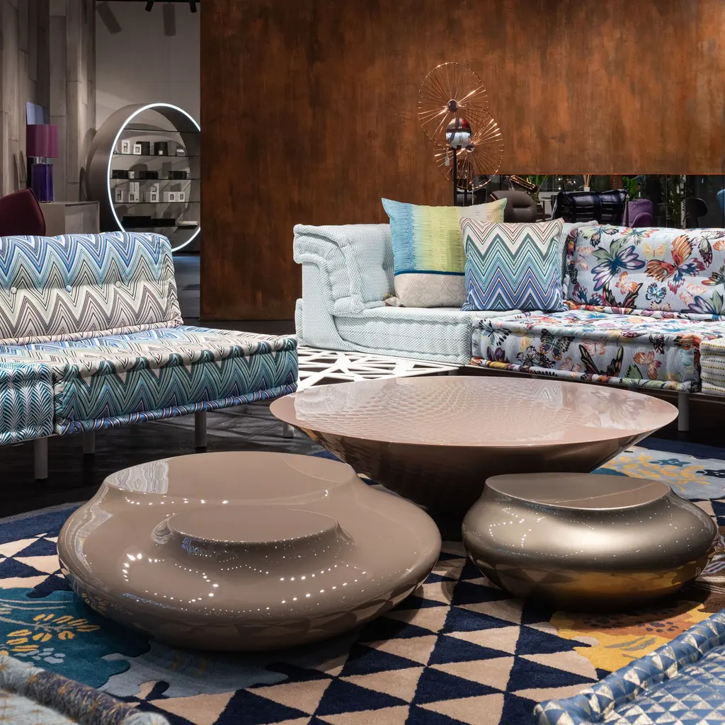 Patterned sofas and low tables are grouped in a furniture showroom.