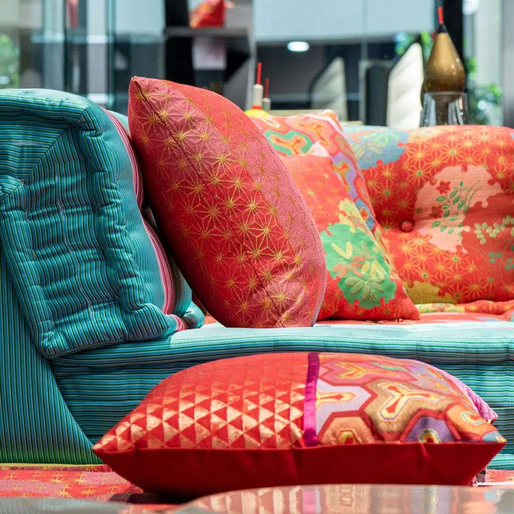 Colorful cushions are arranged on a striped sofa in a home-furnishings display.