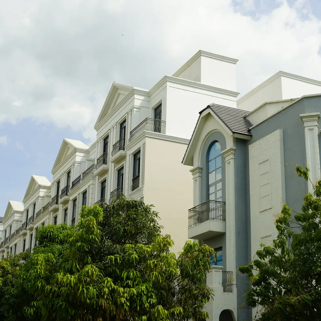 Residential buildings with balconies, large windows and landscaped trees.