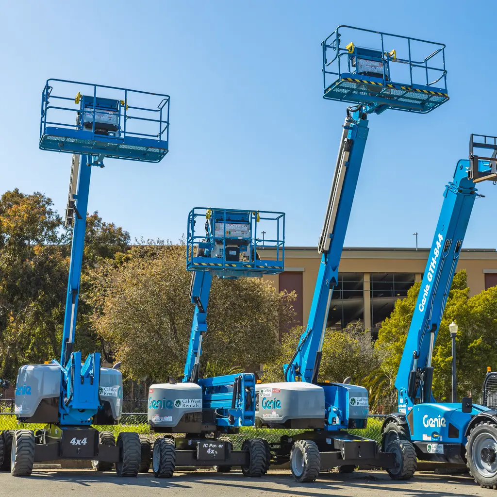A group of boom lifts displayed outdoors with their work platforms raised.