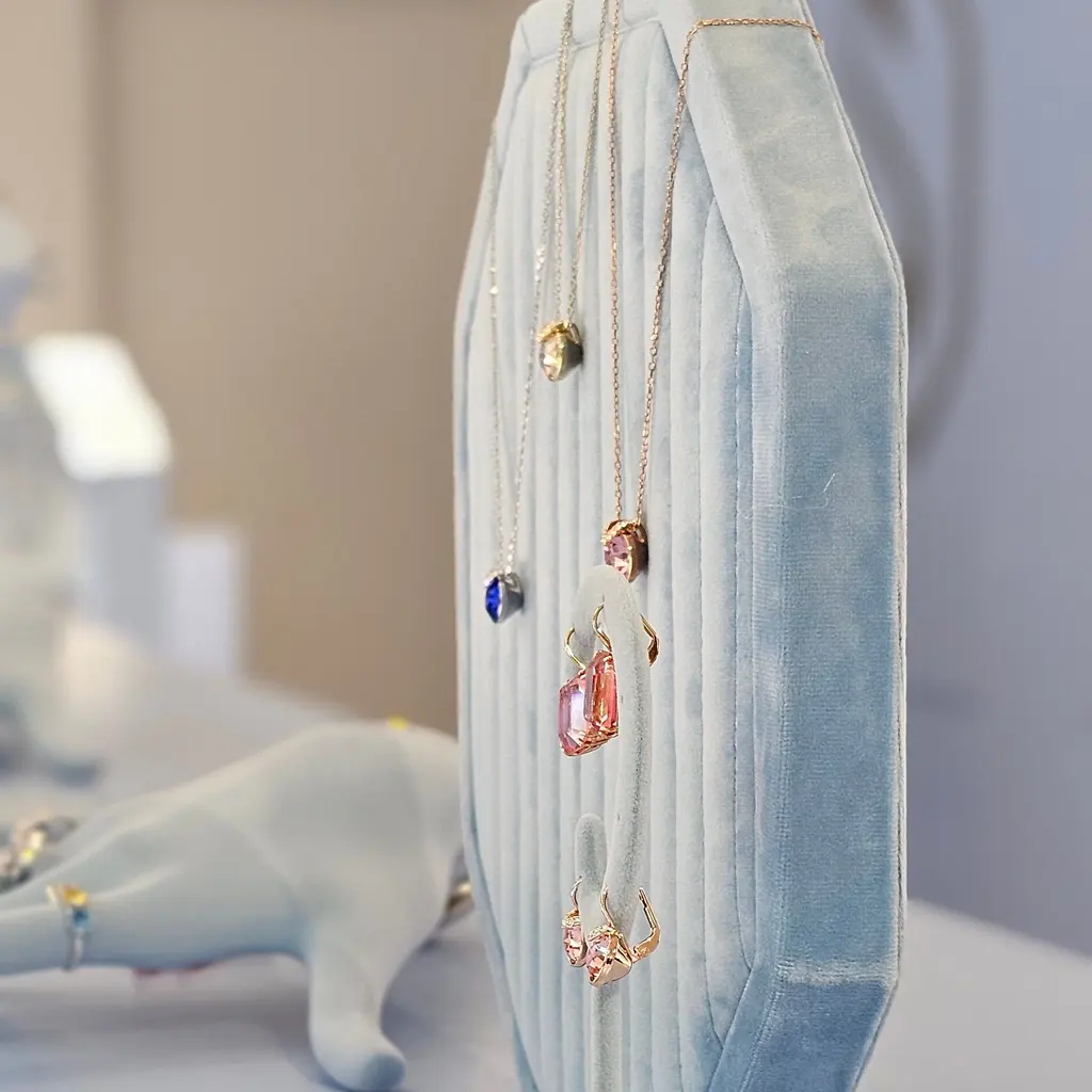 Colored pendant necklaces hang on a padded jewelry-store display.