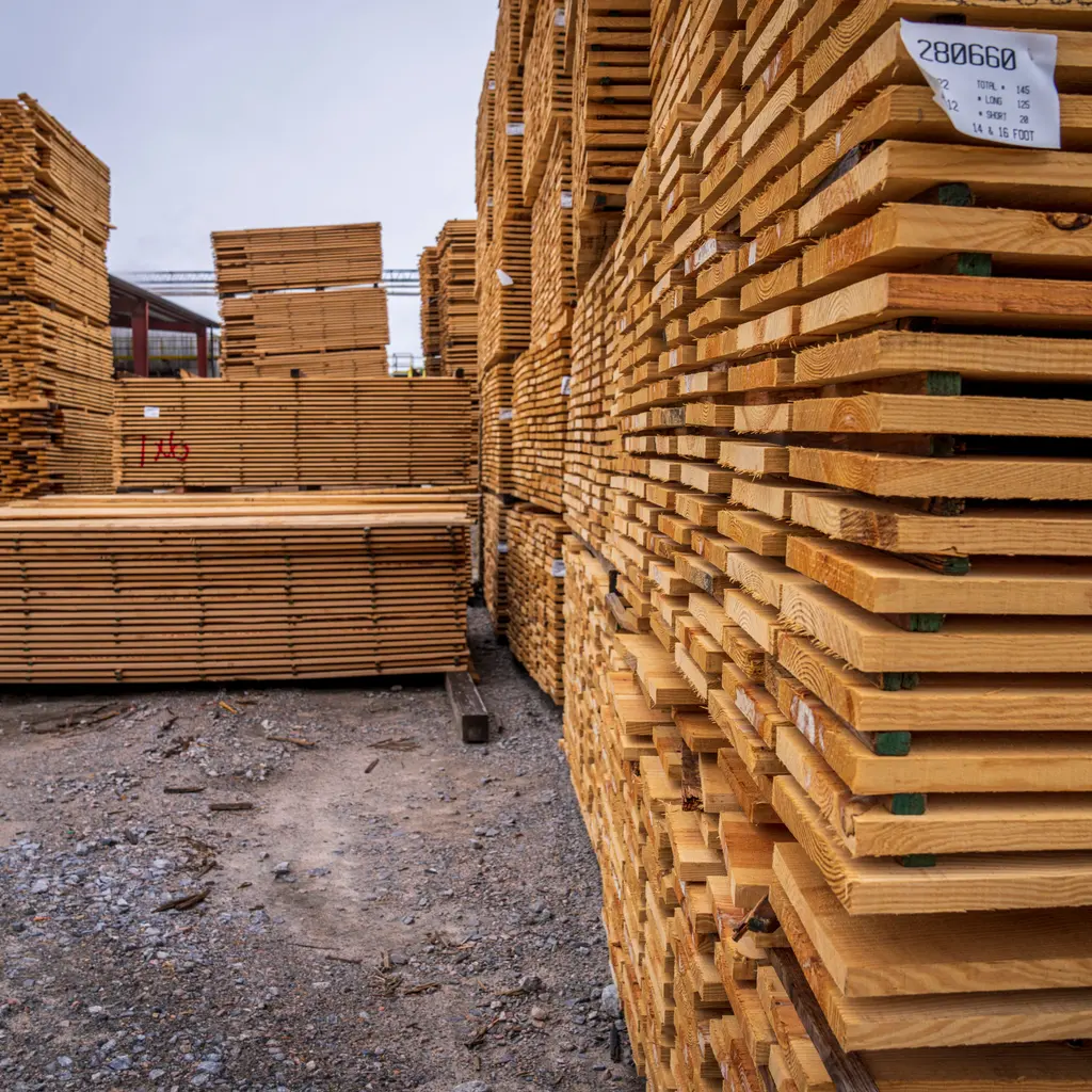 Stacks of wooden boards fill a lumber yard.