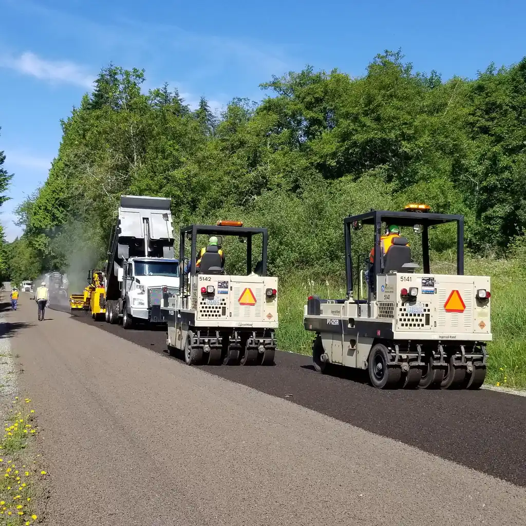 Pneumatic-tire rollers and a dump truck on a road worksite.