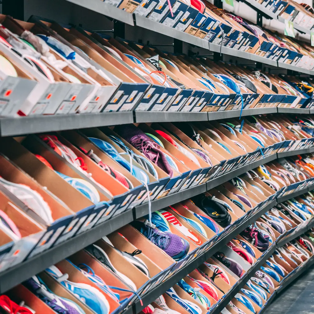 Athletic shoes in open boxes fill several rows of retail display shelving.