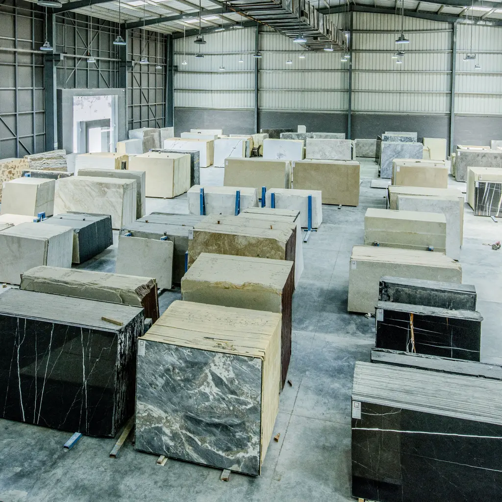 Upright stone slabs stand in rows on warehouse storage racks.