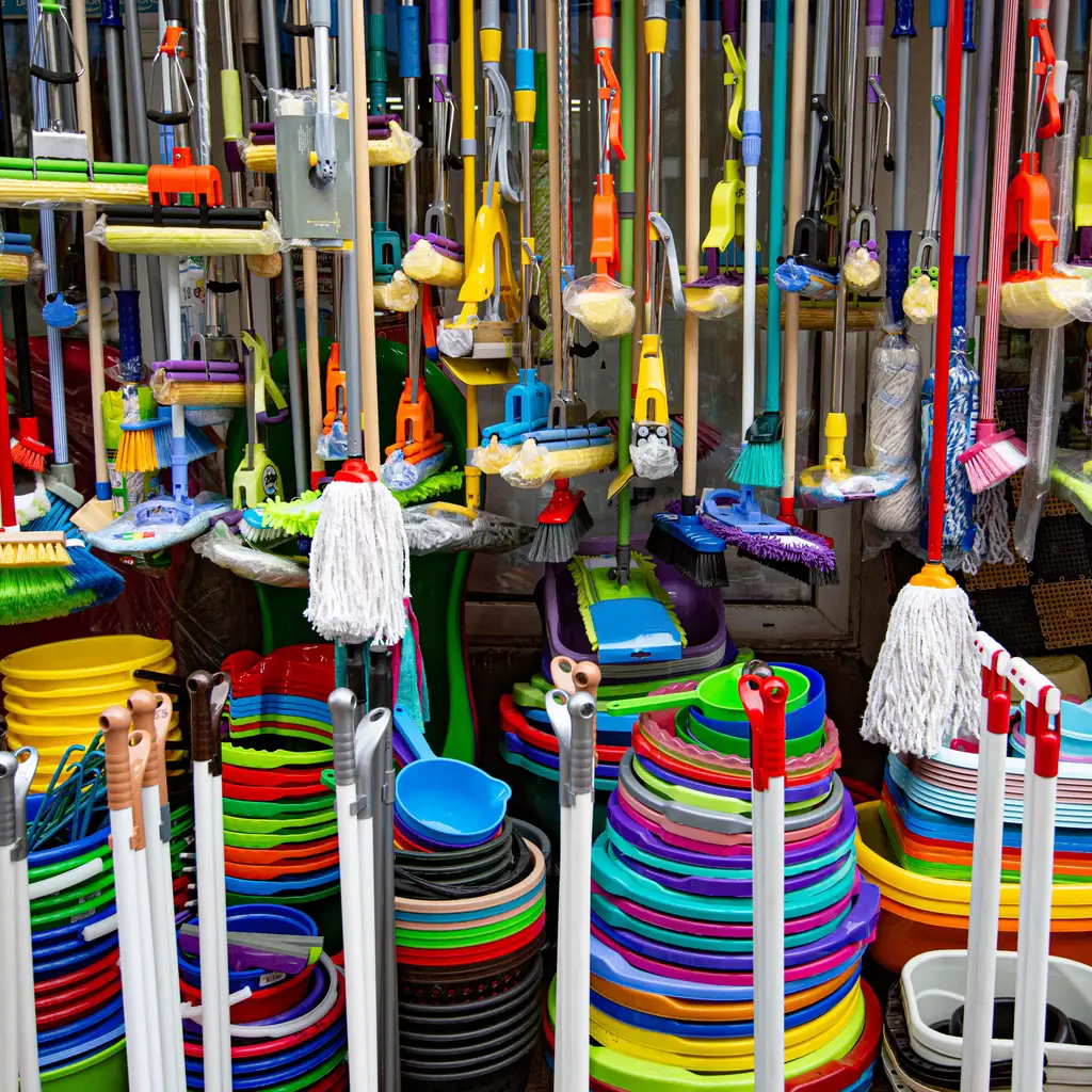 Mops, brushes and buckets packed into a household-goods display.