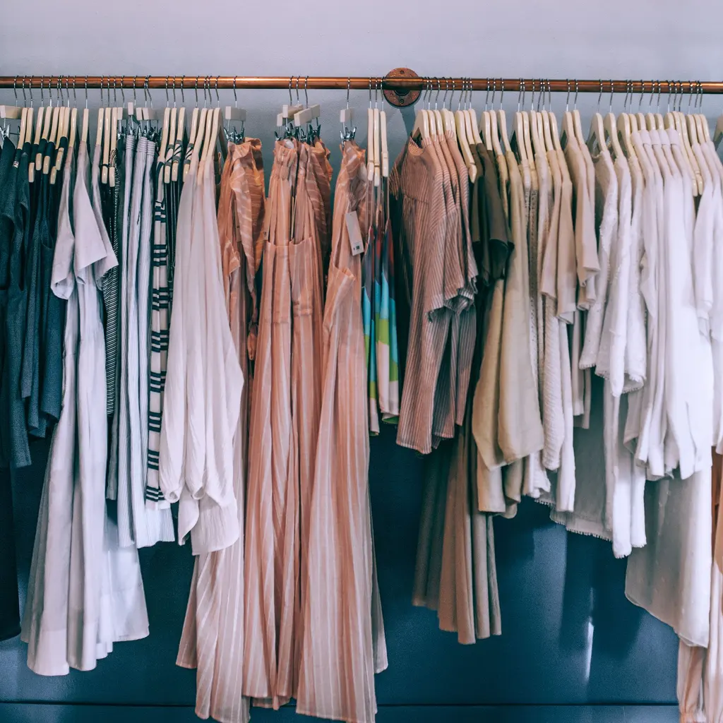 Clothes on hangers line a boutique display rail.