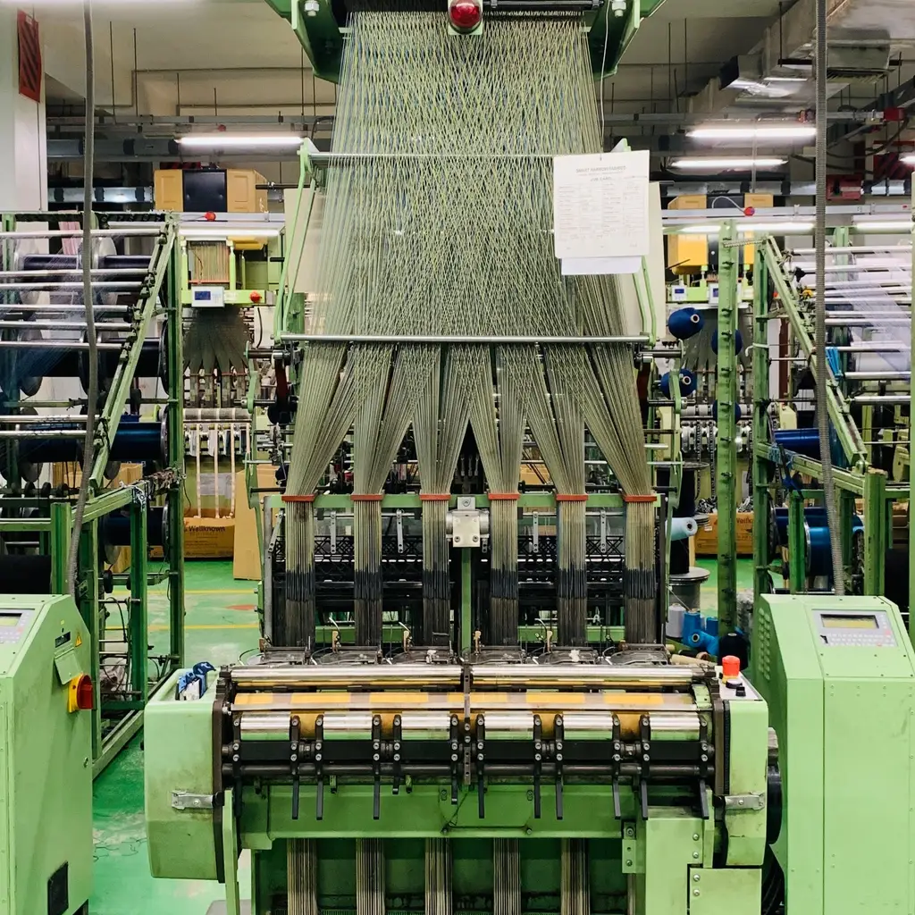 Fiber strands feed through a textile mill machine's guides and roller bank.