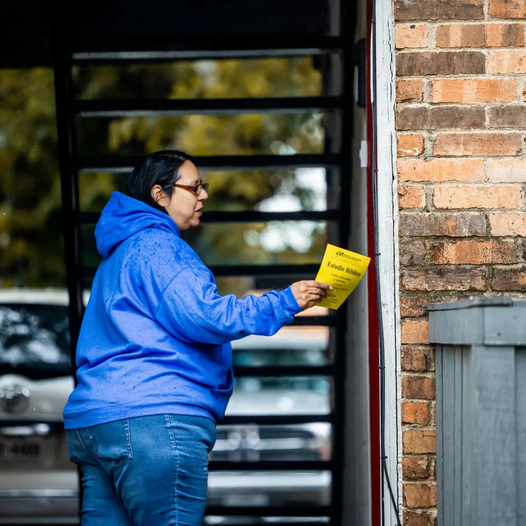 A person delivering a printed flyer at a building entrance.