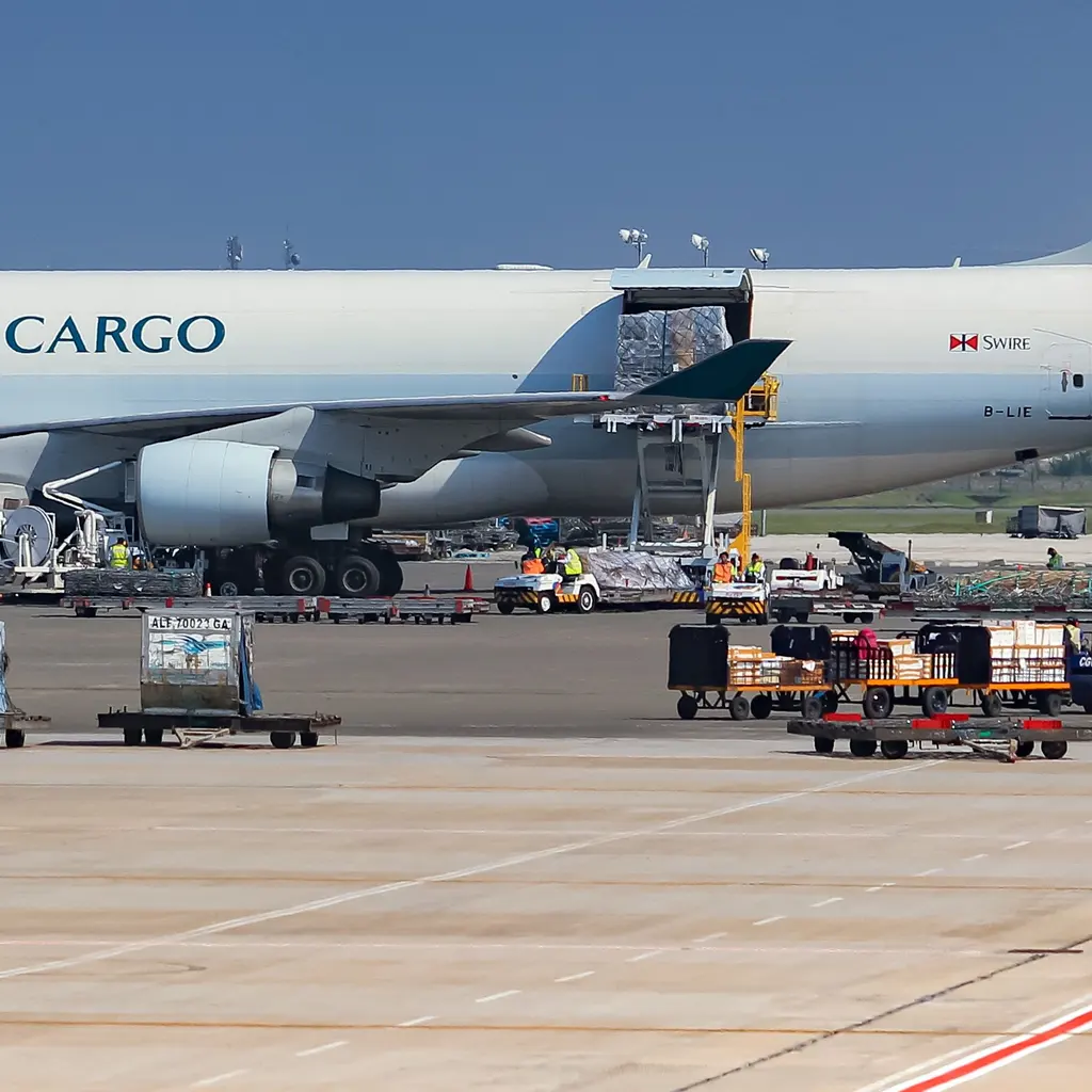 A freight loader at an aircraft cargo door, with containers on the apron.