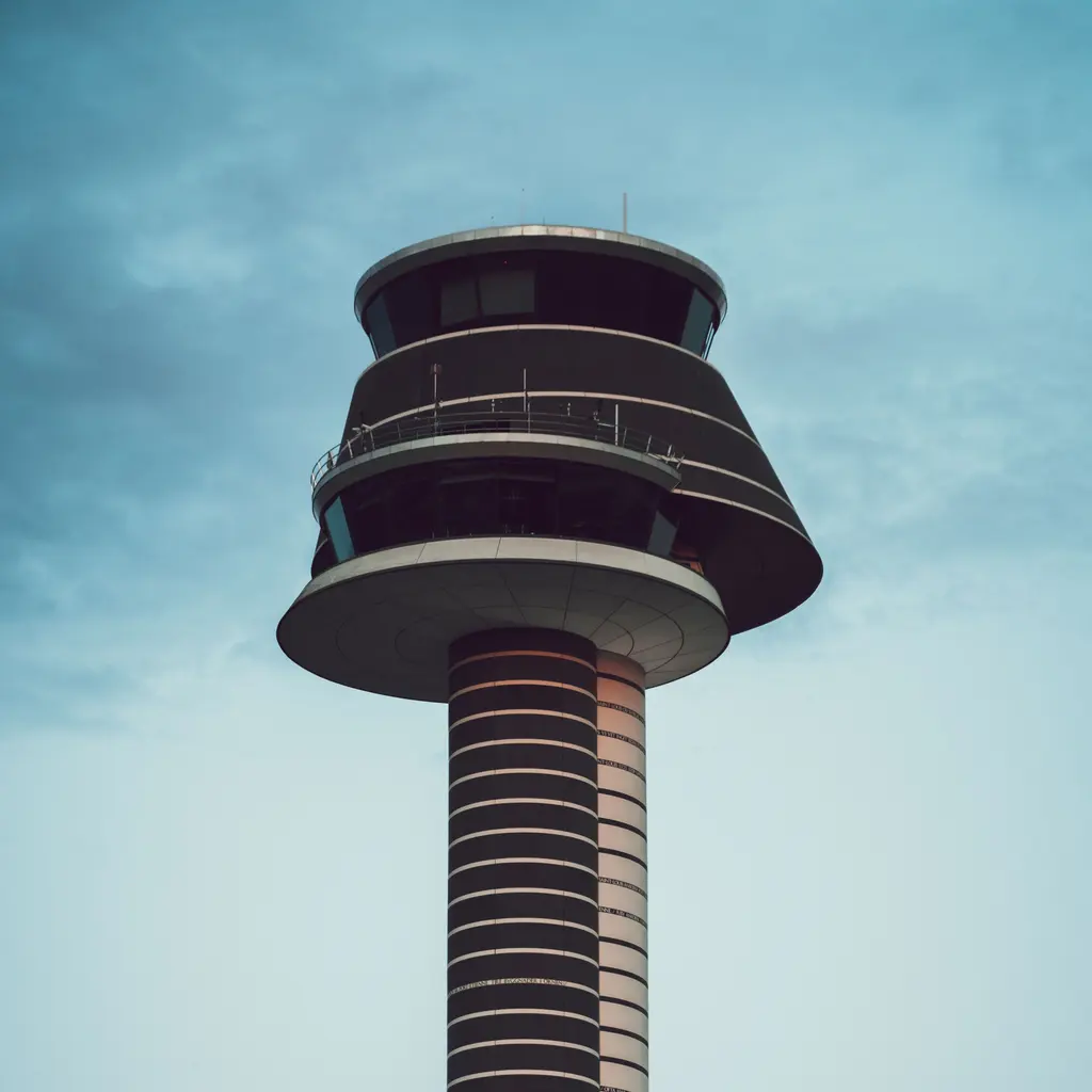 An airport control tower beneath a cloudy sky.