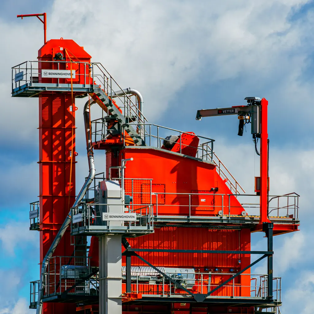 An asphalt mixing tower with aggregate hoppers, steel walkways and pipework.