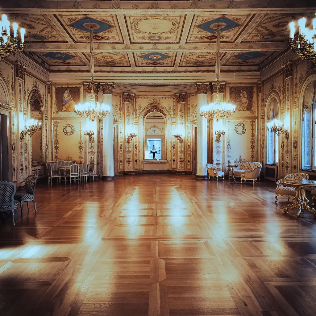 An empty ornate ballroom with chandeliers and a broad polished wooden floor.