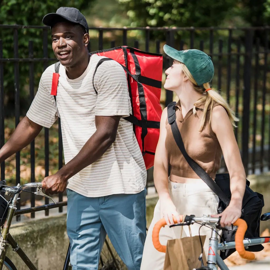 Two bicycle couriers with insulated delivery bags and their bicycles.