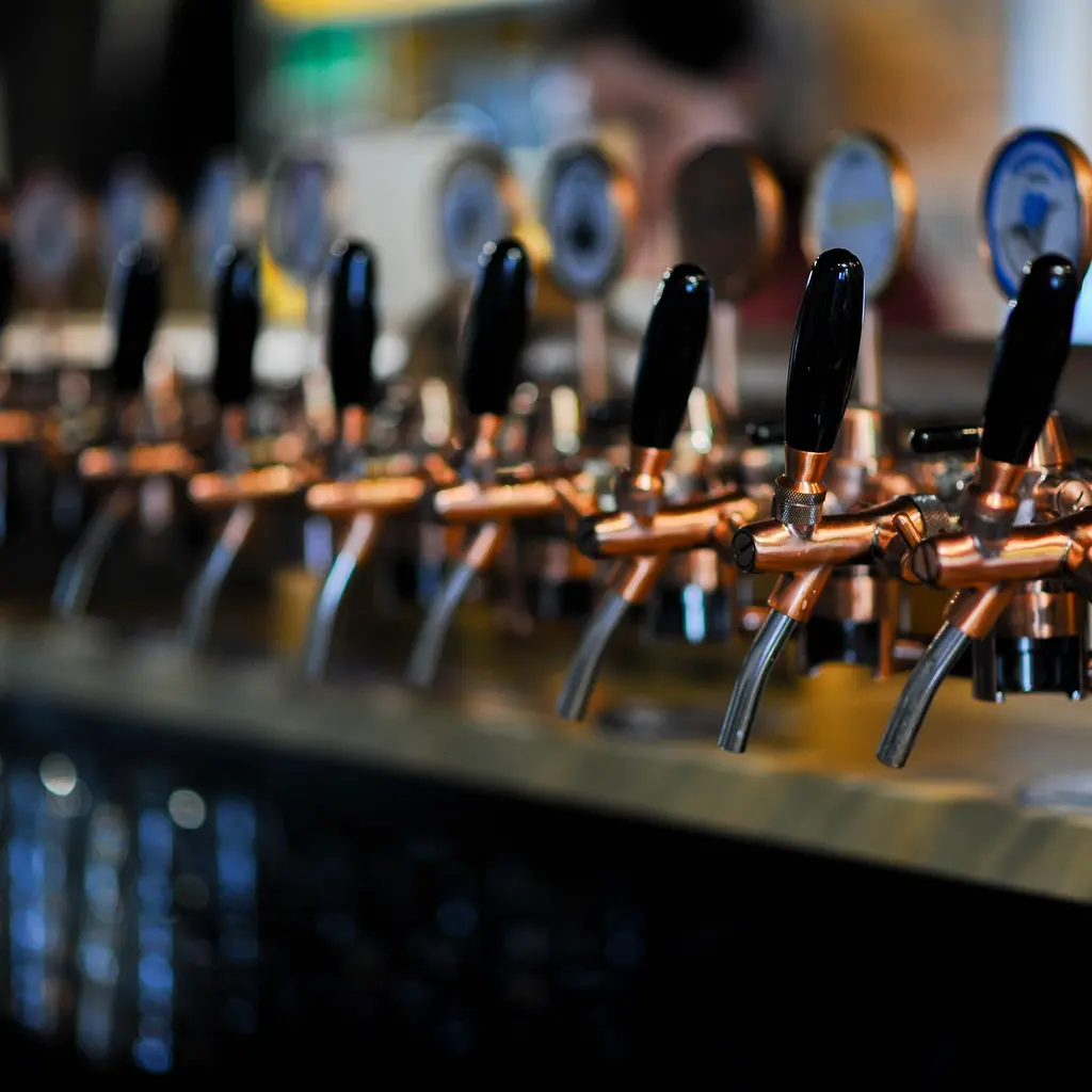A row of copper-colored beer taps behind a bar counter.