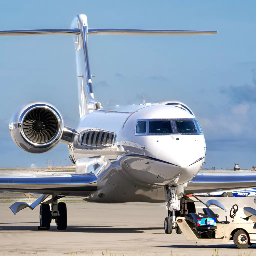 A business jet on the apron beside ground-support equipment.