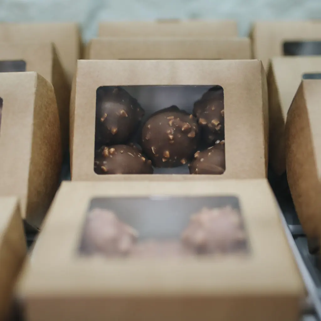 Chocolate confections packaged in windowed cardboard boxes.