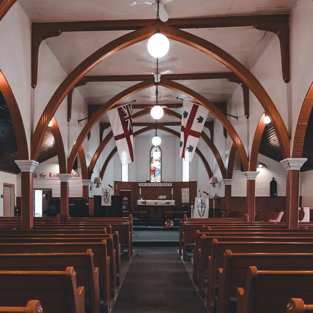 Rows of wooden pews leading to the altar inside an empty timber-arched church.