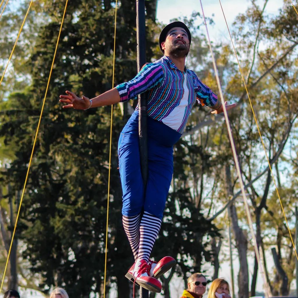 A costumed circus performer balancing outdoors with arms extended.
