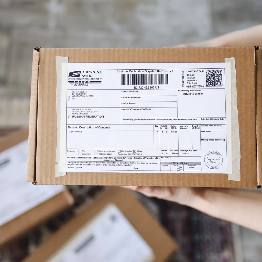 A shipping and customs declaration attached to a parcel held ready for dispatch.
