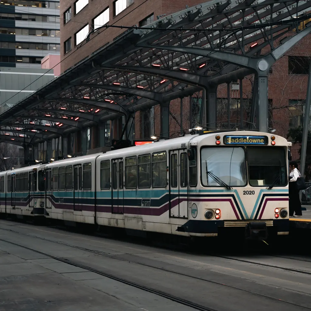 A light-rail train beside a covered urban station platform.