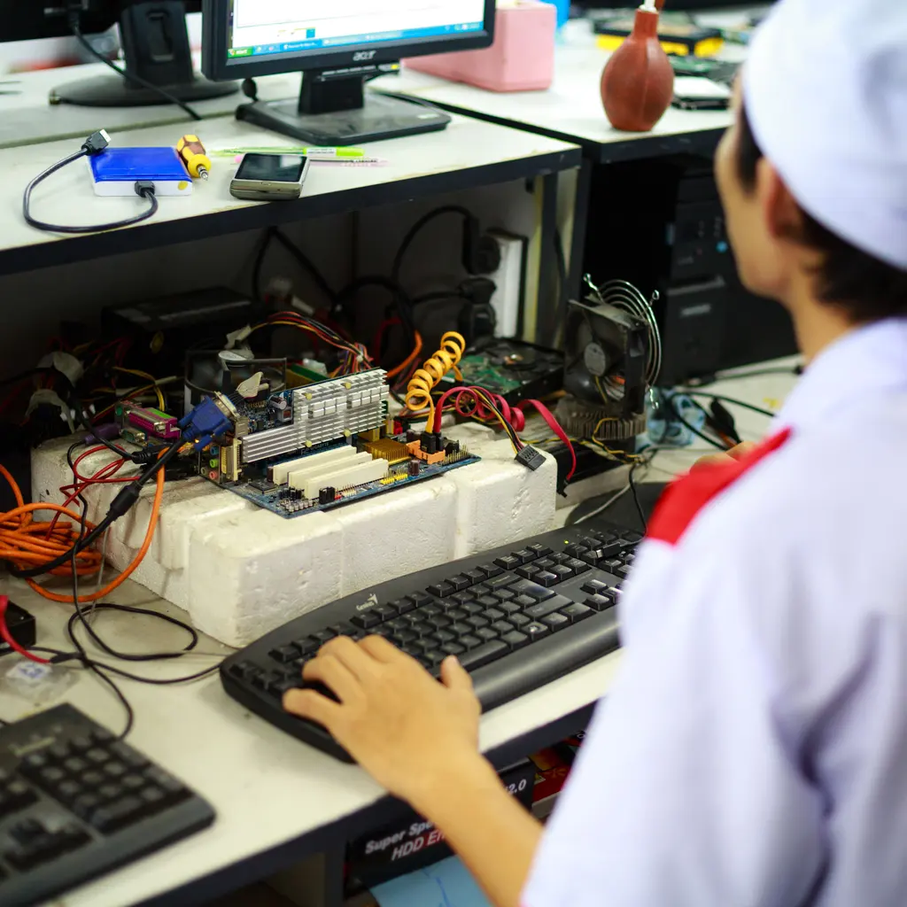 A person operating a keyboard at a computer-component testing bench.