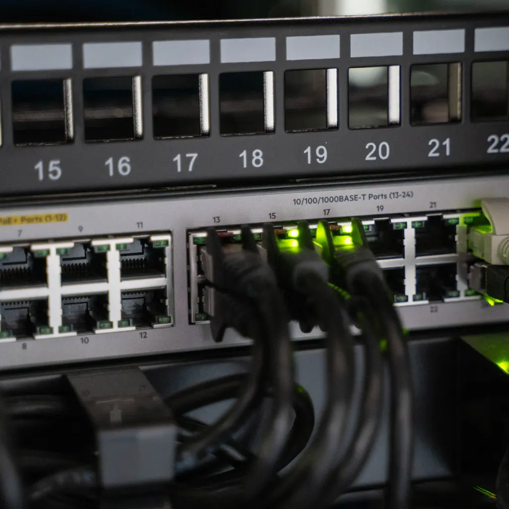 Ethernet patch cables connected to an illuminated network switch.