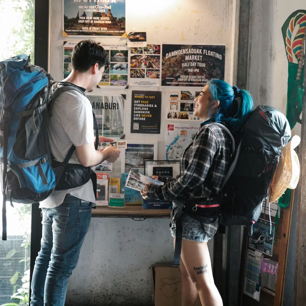 Backpackers reading a wall display of local visitor information.