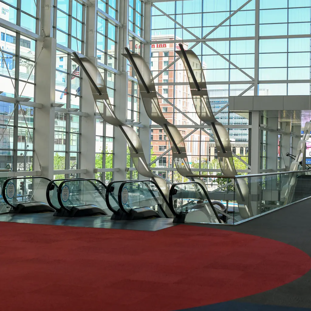 Escalators and a broad carpeted concourse inside a glass-fronted convention center.