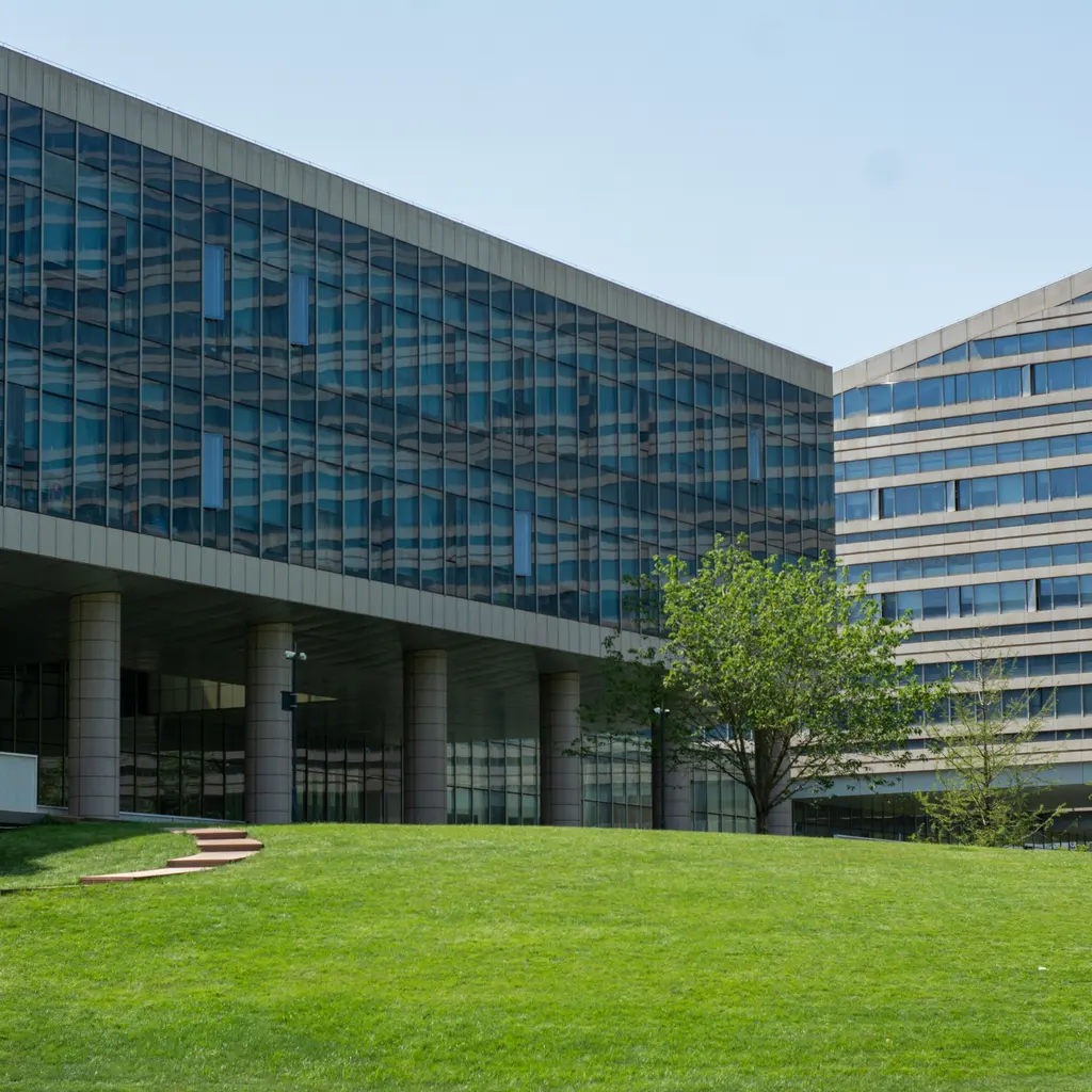 A glass-fronted office complex surrounding a landscaped lawn.